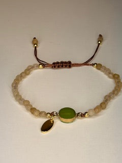 Bracelet with natural colored beads and a green stone on a white background 