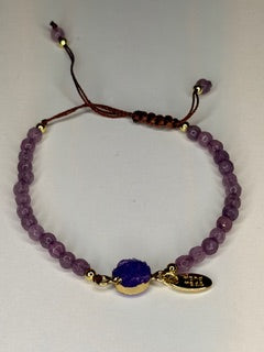 Purple beaded bracelet with a purple stone on a white background