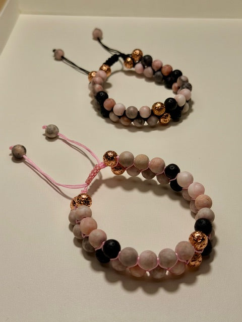 Two beaded bracelets with pink, black, and copper beads on a light background
