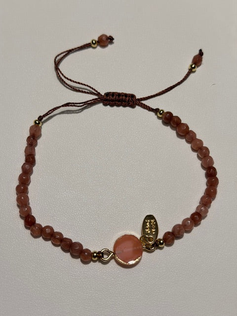 Bracelet with dusty pink beads and a pink stone on a light gray background