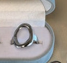 Silver ring displayed on a beige surface .