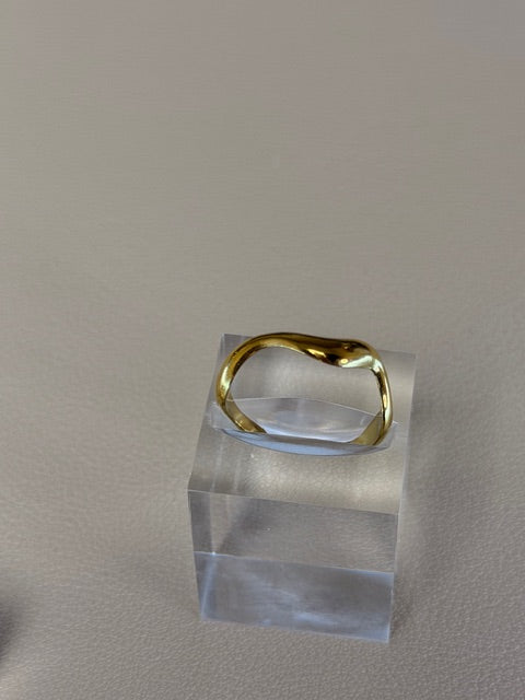 Gold ring on a clear acrylic block against a gray background