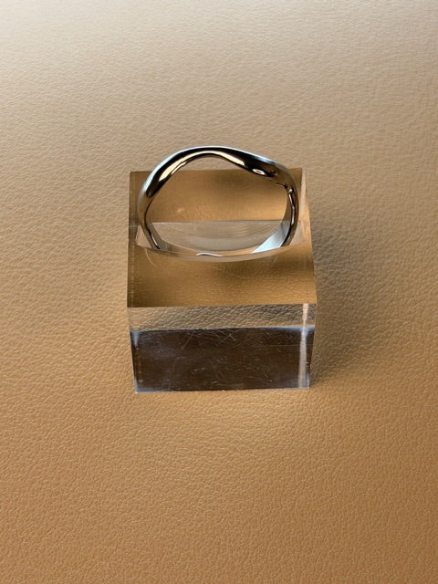 Silver open ring on a beige background.