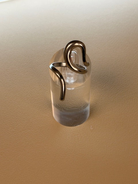 Irregular open ring on a clear stand on a beige background