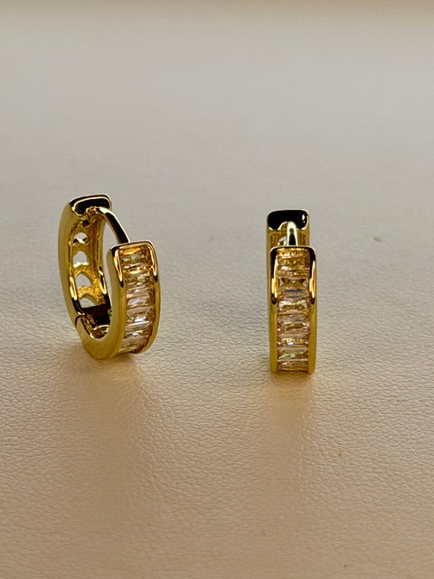 Gold hoop earrings on a beige background