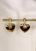 Gold heart-shaped earrings with embedded stones on a light background