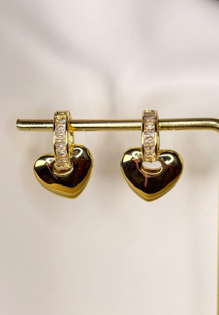 Gold heart-shaped earrings with embedded stones on a light background