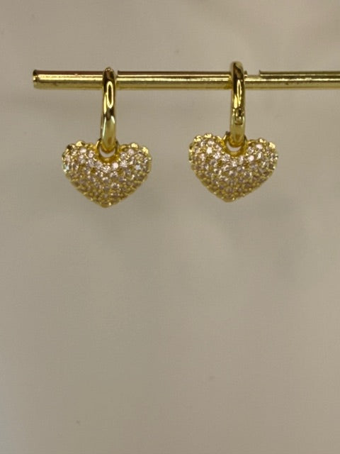 Gold heart-shaped earrings on a beige background