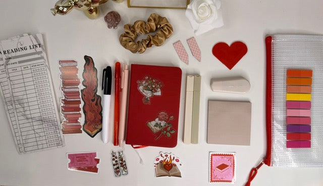 Collection of stationery items including a red pouch, scissors, and decorative elements on a white surface.