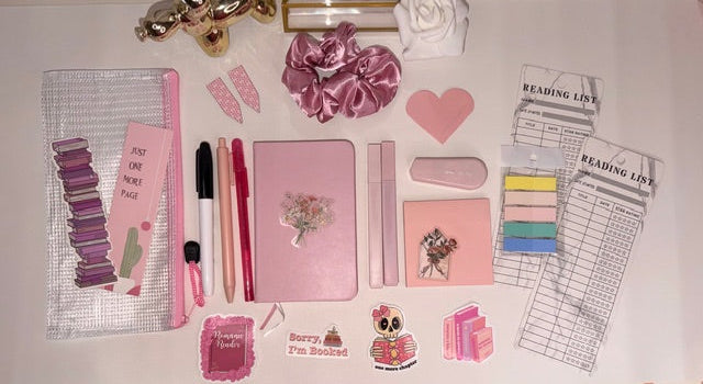 Collection of stationery items including notebooks, pens, and decorative elements on a white surface.