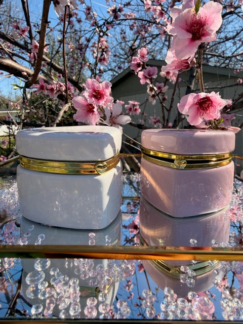 Pink and white cylindrical containers with gold accents against a cherry blossom background