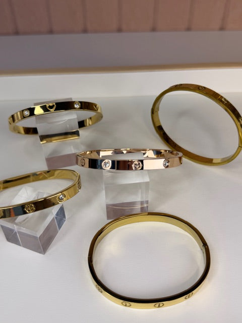Gold bracelets displayed on a white surface with a neutral background